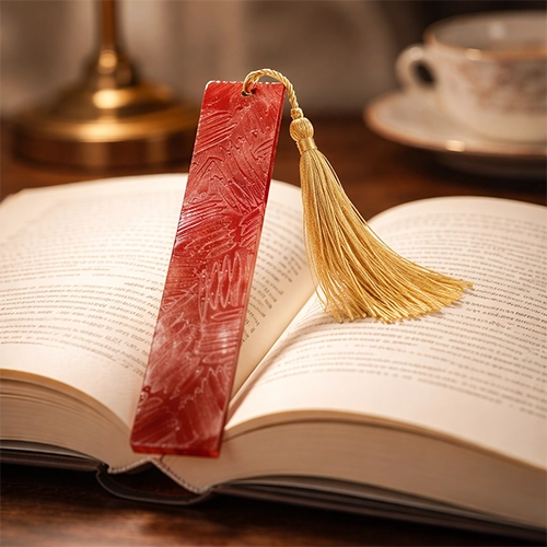 Marque-page artisanal en résine rouge avec pompon doré